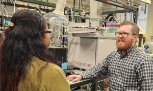 Dr. Harris and a student talking in a lab with machinery